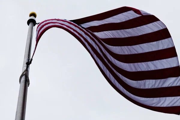 風からの素敵な曲線でオーバーキャストスカイに対する米国の旗と旗竿 — ストック写真