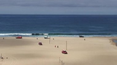 Red Beach Rescue Trucks Moving Across Sand With Lights Flashing Approaching Fire Engine And Ambulance