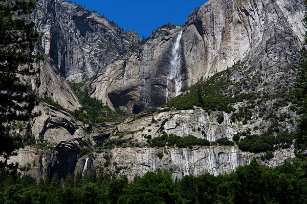 アッパー ローワーヨセミテ滝国立公園カリフォルニア花崗岩の岩壁緑の木と青い空 — ストック写真