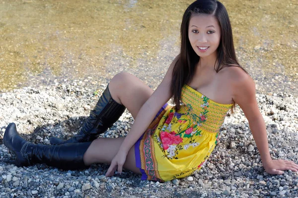 Asian American Woman Sitting Rock Shore River Yellow Dress Black — Stock Photo, Image