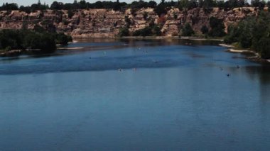 Arka planda kayalıklar olan American River California 'daki uzak kayıklar