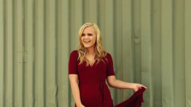 Kırmızı elbiseli, yeşil metal duvarlı, beyaz, genç bir kadın. 