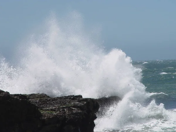 Ocean Wave Rociando Sobre Black Shore Rock Con Cielo Azul — Foto de Stock