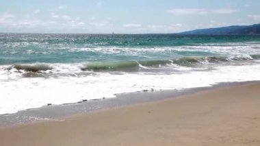 Okyanus Dalgaları Sahili ve Mavi Gök Santa Monica California Beyaz Bulutlar ve Yelkenli Tekne Çekimi