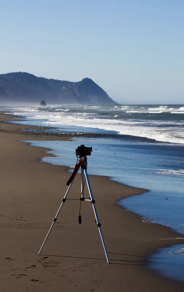 海の波と青い空とビーチでヒルズを指す三脚上のカメラ — ストック写真