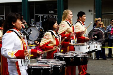 Erkekler ve kızlar küçük kasaba yürüyüşü için bandoda davul çalıyorlar.
