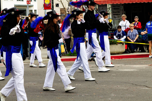 Teen Girls And Boy Playing Musical Instruments In Marching Band Small Town Parade