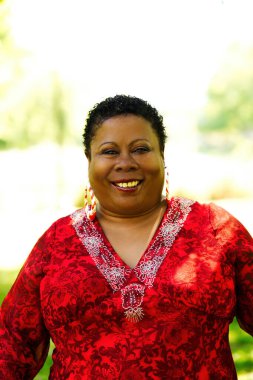 Orta yaşlı, kırmızı bluzlu ve küpeli Afro-Amerikan Kadın.