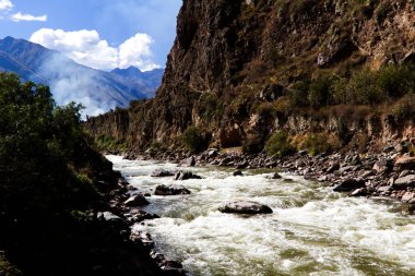 Urubamba Nehri Peru 'nun güneyindeki kayaların üzerinden duman ve beyaz bulutlarla akıyor.