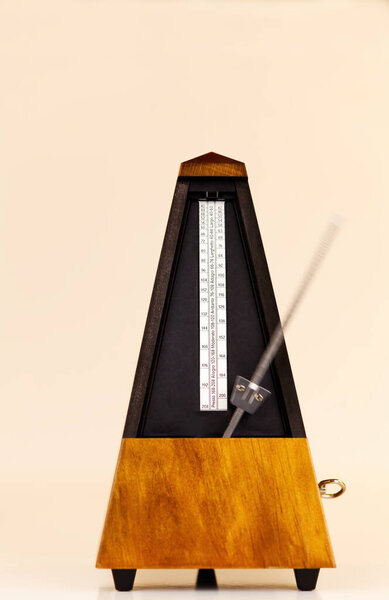 Деревянный механический метроном на светлом фоне с размытым движением металлической руки
