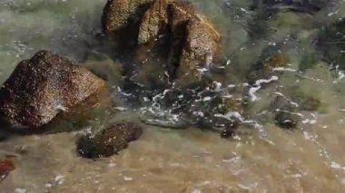 Sahilde dalgalar üzerlerini kaplarken kayaların sıkıca çekilmiş görüntüsü.