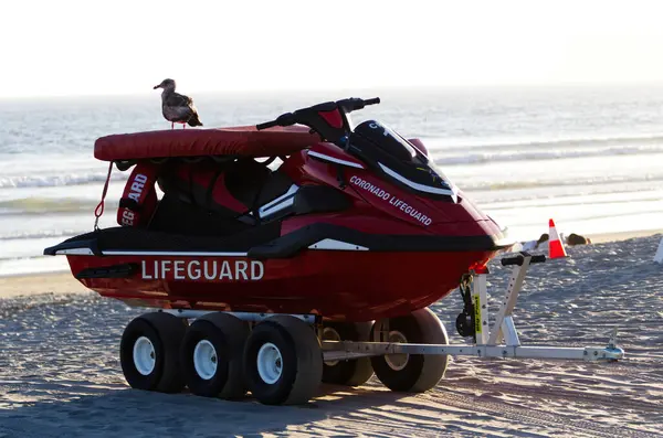 科罗纳多加州红救生员救援艇挂在有背景的海滩上的拖船上 免版税图库图片