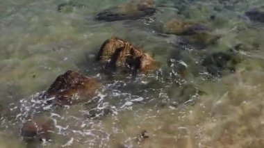 Sahilde dalgalar üzerlerini kaplarken kayaların sıkıca çekilmiş görüntüsü.