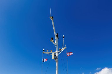 Fransız ve Fransız Polinezyası Bayrakları Mavi Gök ve Beyaz Bulutlu Gemi Direğinden Dalgalanıyor