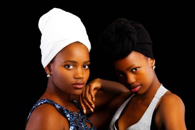 Two African American Women Sisters In Headscarfs Against Black Background clipart