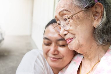 An Asian old mother smiling and happy being hugged by her daughter