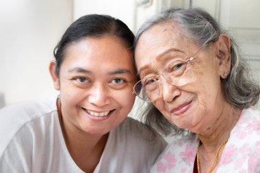 Sağlıklı ve mutlu Asyalı son sınıf öğrencisi ve yetişkin kızı kameraya poz veriyor.