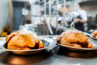 Aşçı ve personelin arka planda çalıştığı bir restoranın mutfağında kızarmış tavuk menüsü hazırlandı.