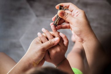 Tırnak makası kullanarak oğlunun tırnaklarını kesmesine yardım eden bir anne 