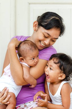 Mutlu Güneydoğu Asyalı güzel bir annenin iki küçük çocuğuyla portresi.
