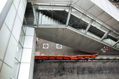 Şehir yolunun yanındaki banliyö tren istasyonuna giden merdivenler ve köprü. Trafik barikatı var ve park işareti yok.