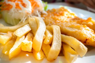 Close-up plate of fish and chips menu with salad served as lunch meal at a restaurant clipart