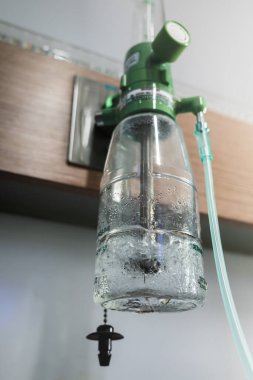 Acil durum desteği için hastane koğuşunda nemlendirici şişeli, duvara monte edilmiş tıbbi oksijen silindirli düzenleyici.