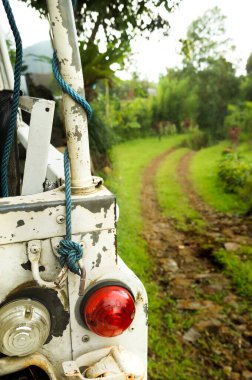 Ormana giden patikanın kenarına park edilmiş eski bir arazi aracı. Macera konsepti.