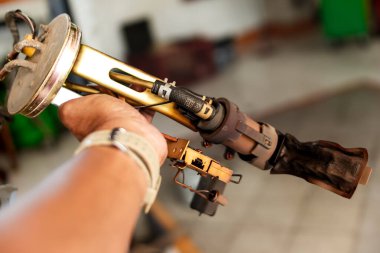 Otomotiv atölyesinde tıkanmış yakıt filtresi montajı gösteren bir araba tamircisi.