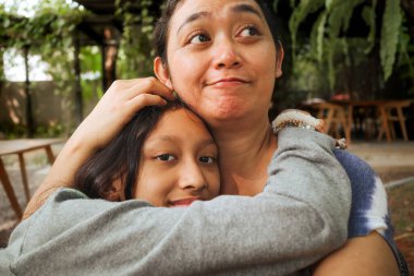 Anne ve kız arasındaki Asyalı aile sevgisi ve sevgi, birbirini şefkatle kucaklıyor.