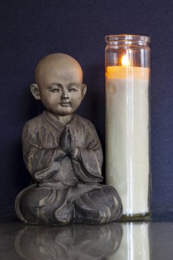 Elinde mum olan Buda figürü.