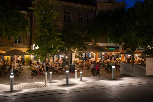 リュブリャナ スロベニア 2022年7月14日 レストランテーブルで夏の夜の食事を楽しむ人々のグループペトコフスコヴォ ナブレッツェ川沿いの夜 ブッチャー橋からの眺め ストックフォト