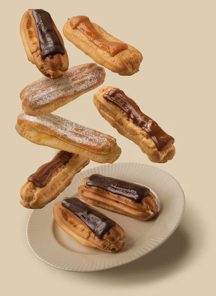 Flying freshest chocolate cocoa, powdered sugar, condensed milk eclairs on brown background. The concept of delicious chocolate, cocoa, powdered sugar, condensed milk eclairs that just fly away.