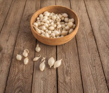 Basket of Snowball onion sets on weathered wood background. Organic garden planting for seasonal harvest. Flat lay composition highlighting natural farming and homegrown vegetable cultivation.
