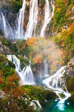 Plitvice göllerindeki yağmurlu, sisli sonbahar havasında sakin bir orman ortamında resim gibi sonbahar şelalesi.