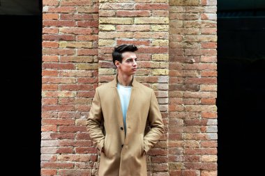 Sokakta kışlık kıyafetler giyen genç bir adam..