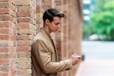 Sokakta kışlık kıyafetler giyen genç bir adam. Modern saç stili, kahverengi ceketli genç adam..