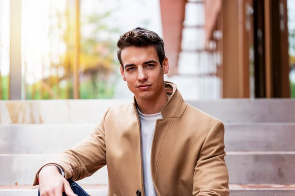 stock image Portrait of stylish young man with coat sitting on a stairs