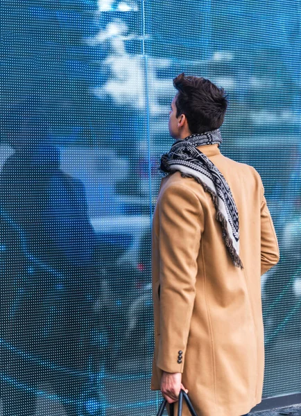 ストリートでリードパネルを見て立ってコートを着たスタイリッシュな若い男の肖像画 — ストック写真