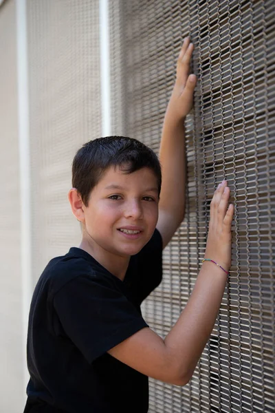 Хлопчик Шортах Чорна Футболка Спирається Стіну Дивлячись Камеру — стокове фото