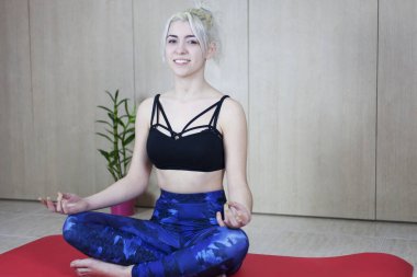 İnsanlar, meditasyon ve rahatlama. Çekici, gülümseyen, üstsüz, pantolonlu, spor paspasında oturan sarışın kadın.,