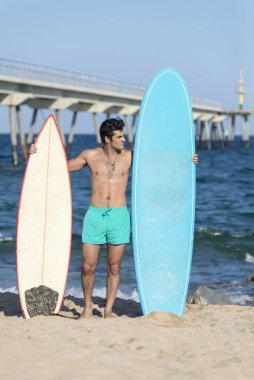 Plajda elinde sörf tahtası olan çıplak bir sörfçü.