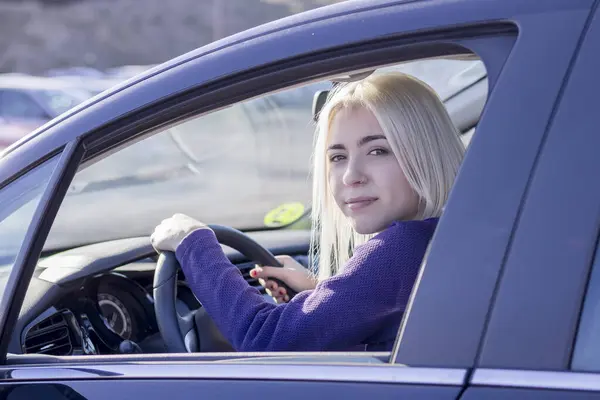 Young Blonde Female Driver Wearing Purple Sweater Sitting Confidently Wheel Stockfoto