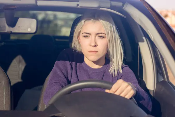 Concentrated Young Blonde Woman Wearing Purple Sweater Driving Car Focused Stockfoto