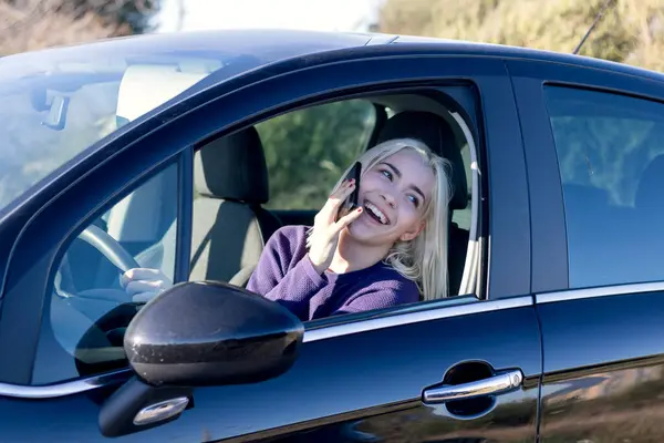 자동차의 운전석에 앉아있는 그녀의 전화에 보라색 스웨터에 금발의 로열티 프리 스톡 이미지