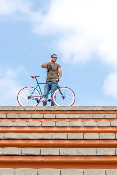 Confident Man Rooftop Holding Bicycle While Talking Phone Clear Sky Стокова Картинка