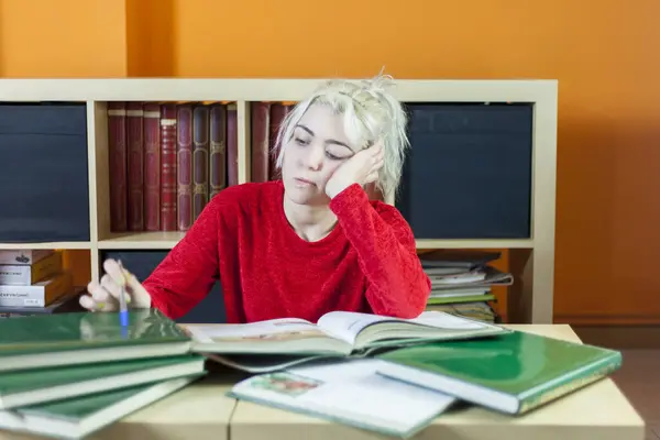 Young Woman Blonde Hair Looking Tired Holding Pen While Reading Stockfoto