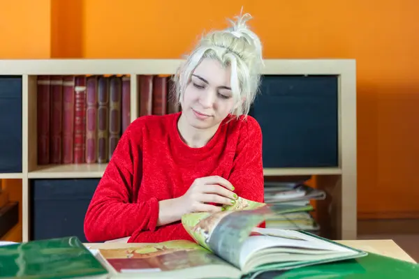 Young Woman Bleached Blonde Hair Focusing Reading Dressed Red Sitting Royaltyfria Stockbilder