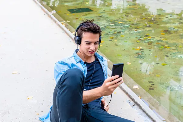 Young Man Headphones Uses Smartphone Pond Wearing Denim Shirt Black Royalty Free Εικόνες Αρχείου