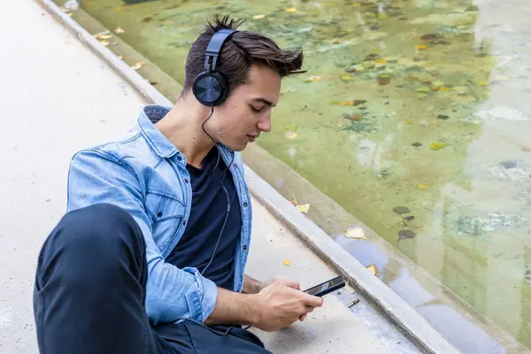 Young Man Headphones Uses Smartphone Pond Wearing Denim Shirt Black Φωτογραφία Αρχείου